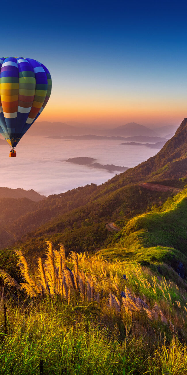 Landscape of morning fog and mountains with hot air balloons at sunrise.